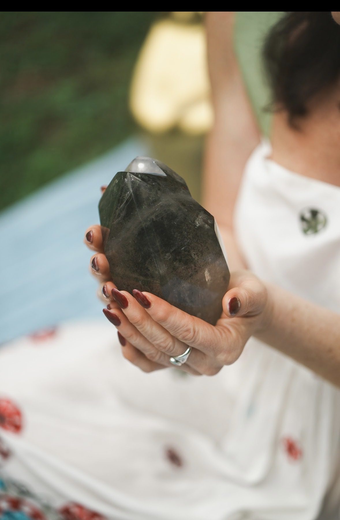 Person holding large, dark crystal outdoors.